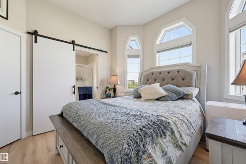 Light wood-finish flooring, white barn door, arched windows, and white walls - #3 150 Everitt Dr N, St. Albert, AB 
