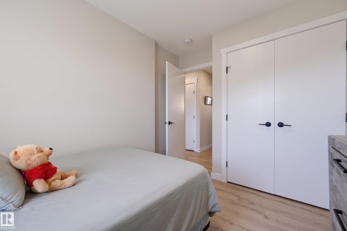 Light wood-finish flooring, white bifold closet doors, matte black hardware, light neutral wall paint, and white trim - #3 150 Everitt Dr N, St. Albert, AB 