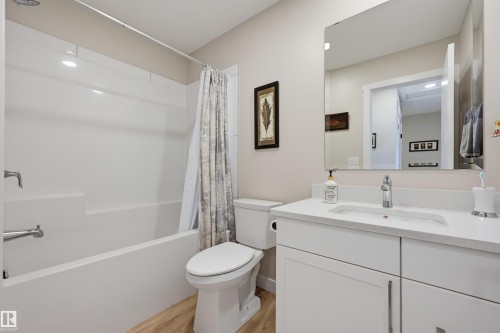 Bathroom featuring a full-size bathtub, white vanity with integrated sink, chrome fixtures, and wood-finish flooring - #3 150 Everitt Dr N, St. Albert, AB 