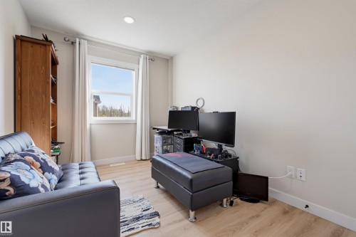 Bright secondary bedroom featuring wood-finish flooring, large window with natural light, and built-in storage cabinetry - #3 150 Everitt Dr N, St. Albert, AB 