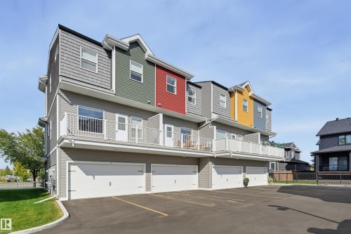 Multi-level exterior with varied siding, private balconies, individual garage doors, and a paved parking area - #3 150 Everitt Dr N, St. Albert, AB 