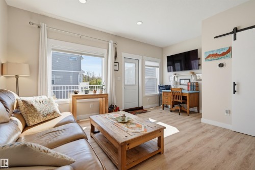 Wood-finish flooring, recessed lighting, and a white sliding barn door - #3 150 Everitt Dr N, St. Albert, AB 