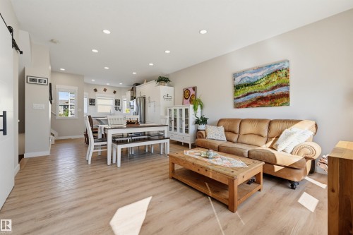 Open-concept living space featuring wood-finish flooring, recessed lighting, and light-colored walls - #3 150 Everitt Dr N, St. Albert, AB 