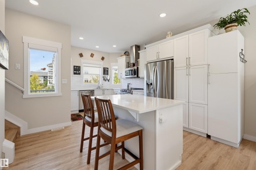 White shaker cabinetry, stainless steel refrigerator, white subway tile backsplash, recessed lighting, and wood-finish flooring - #3 150 Everitt Dr N, St. Albert, AB 