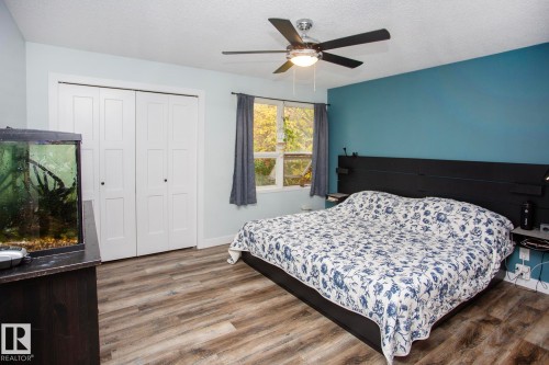 Wood-finish flooring, white bi-fold closet doors, ceiling fan with integrated lighting, and a prominent window - 8 Ash Crescent, St. Albert, AB 