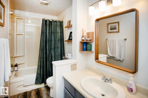 Tub-shower combination with a durable surround, wood-finish flooring, vanity with integrated sink, and an overhead light fixture - 8 Ash Crescent, St. Albert, AB 