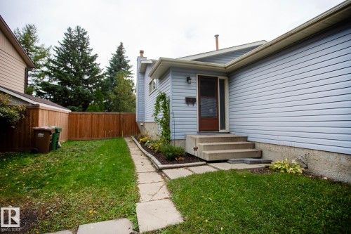 Light blue horizontal siding with a brown entry door, concrete steps, and a concrete paver pathway - 8 Ash Crescent, St. Albert, AB 
