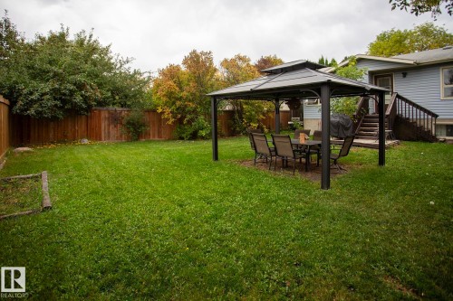 Expansive backyard with a manicured lawn, full privacy fencing, and a built-in gazebo - 8 Ash Crescent, St. Albert, AB 