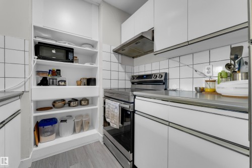 Kitchen featuring white shaker-style cabinetry, a stainless steel range, a stainless steel range hood, and white square tile backsplash - #113 2508 50 St Nw, Edmonton, AB 