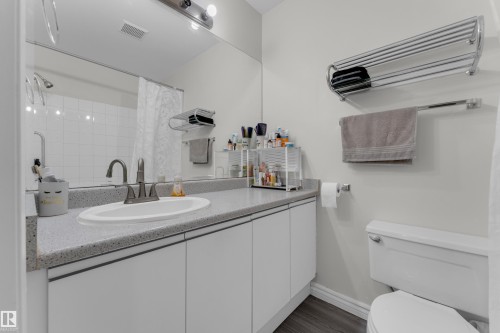 Bathroom featuring a vanity with an integrated sink, a speckled countertop, and white cabinetry - #113 2508 50 St Nw, Edmonton, AB 
