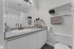 Bathroom featuring a vanity with an integrated sink, a speckled countertop, and white cabinetry - 