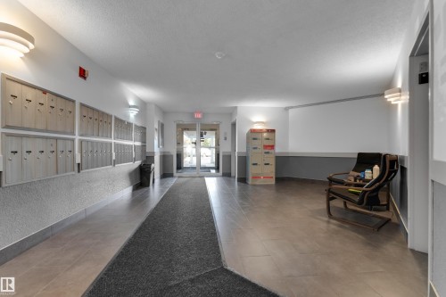 Entryway featuring neutral-toned tile flooring, wall-mounted mailboxes, and recessed lighting - #113 2508 50 St Nw, Edmonton, AB 