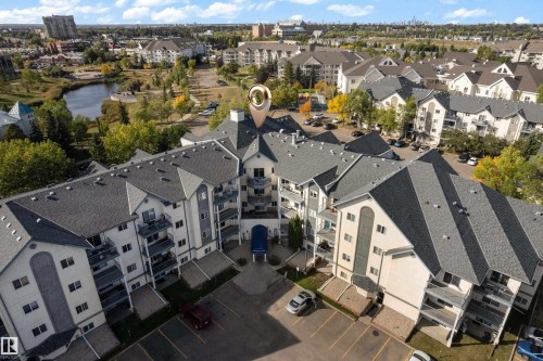 Multi-story building with balconies, gray shingle roofing, and a prominent front entrance awning - #113 2508 50 St Nw, Edmonton, AB 