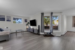 Spacious living area featuring wood-finish flooring, white walls, and bright windows - 