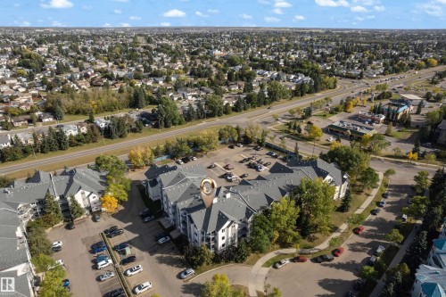 Multi-story apartment building with dedicated surface parking, surrounded by mature trees and a paved street network - #113 2508 50 St Nw, Edmonton, AB 