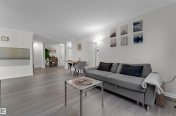 Spacious living area featuring wood-finish flooring, white crown molding, and neutral wall tones - 