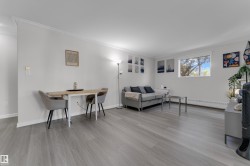 Light wood-finish flooring, white walls, crown molding, and a visible window - 