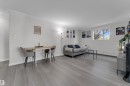 Light wood-finish flooring, white walls, crown molding, and a visible window - #113 2508 50 St Nw, Edmonton, AB 