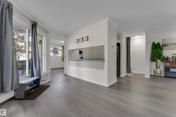Wood-finish flooring, white crown molding, white baseboards, and a pass-through window with tile detail - 