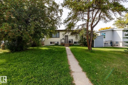 Front exterior with light-colored siding, dark trim windows, and a concrete walk-up leading to the entrance - 10972 157 Street Nw, Edmonton, AB 