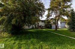 Expansive green lawn with mature trees and a paved walkway - 