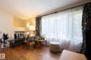 Wood-finish flooring, white spindle railing, and a large window with sheer and patterned curtains - 10972 157 Street Nw, Edmonton, AB 