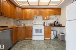 Kitchen featuring wood cabinetry, stainless steel dishwasher, white range, and tiled flooring - 