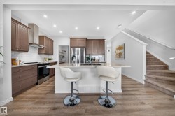 Kitchen featuring wood-finish flooring, recessed lighting, white subway tile backsplash, stainless steel appliances, and a central island with a light-toned countertop - 