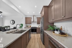 Kitchen featuring wood-finish cabinetry, light-toned countertops, built-in stainless steel appliances, subway tile backsplash, and recessed lighting - 