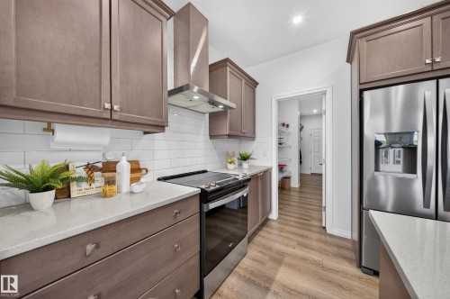 Stainless steel appliances, wood-finish flooring, white subway tile backsplash, light-toned cabinetry, and light-toned countertops - 4104 3 Avenue Sw, Edmonton, AB 