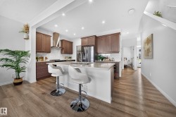 Kitchen featuring wood-finish flooring, full-height cabinetry, stainless steel appliances, a subway tile backsplash, and a central island with a light-toned countertop - 