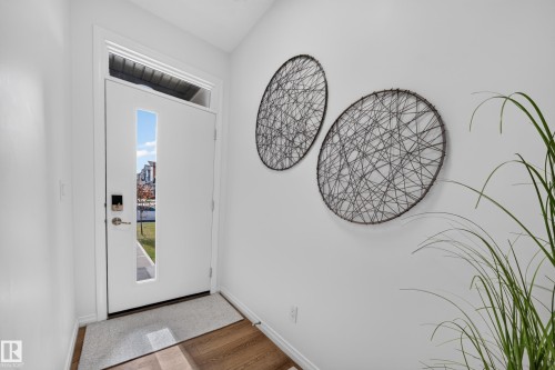 Entryway featuring a white door with vertical glass insert, transom window, and wood-finish flooring - 4104 3 Avenue Sw, Edmonton, AB 