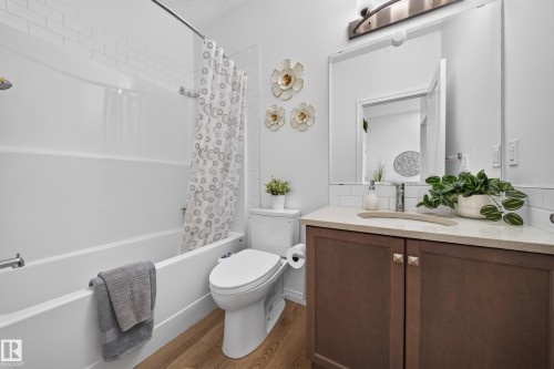 Bathroom featuring a single vanity with wood-finish cabinetry, a stone-finish countertop, and an undermount sink - 4104 3 Avenue Sw, Edmonton, AB 