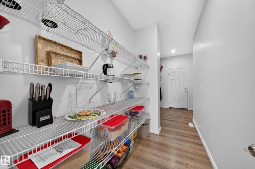 Spacious pantry featuring multiple wire shelving units, light wood-finish flooring, and a paneled interior door - 4104 3 Avenue Sw, Edmonton, AB 