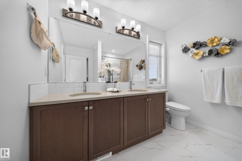 Double vanity with wood-finish cabinetry, light-toned countertop, and undermount sinks - 4104 3 Avenue Sw, Edmonton, AB 