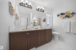 Double vanity with wood-finish cabinetry, light-toned countertop, and undermount sinks - 