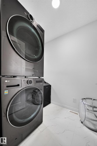 White walls with a single ceiling-mounted light fixture, paired with white tile flooring featuring a subtle gray veining pattern - 4104 3 Avenue Sw, Edmonton, AB 