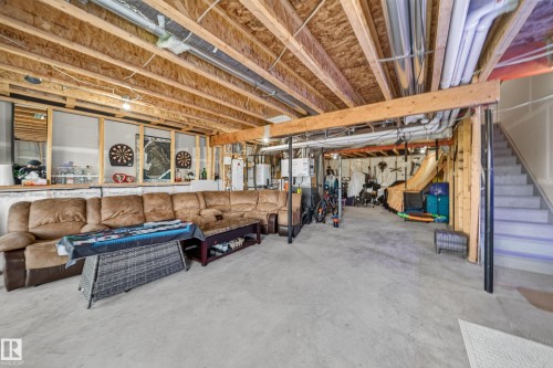 Unfinished lower level featuring exposed wood joists, concrete flooring, and a utility staircase - 4104 3 Avenue Sw, Edmonton, AB 
