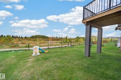 Expansive green lawn with a black chain-link fence and a raised wooden deck with black railings - 