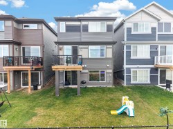 Two-story deck with dark metal railings, vinyl siding, and a grass lawn - 