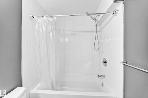 Bathtub with white tile surround, chrome shower rod, and coordinating fixtures - 44 Habitat Crescent Nw, Edmonton, AB 