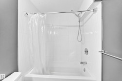Bathtub with white tile surround, chrome shower rod, and coordinating fixtures - 