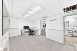 Carpeted room with drop ceiling, white walls, and built-in shelving - 