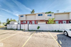 Paved parking area with marked spaces, fronting a two-story building featuring red and beige siding - 