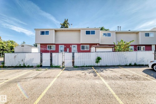Paved parking area featuring yellow stripe markings and a chain-link fence with privacy screening - 44 Habitat Crescent Nw, Edmonton, AB 