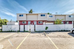 Paved parking area featuring yellow stripe markings and a chain-link fence with privacy screening - 