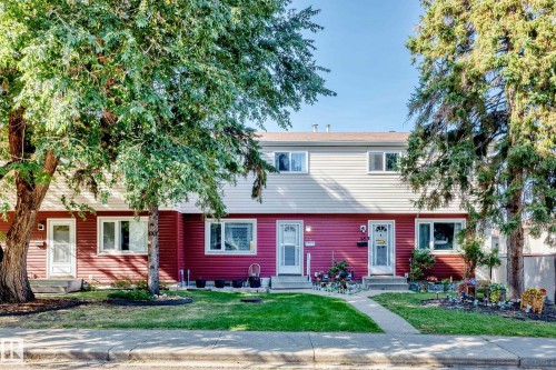 Exterior featuring red and beige horizontal siding, white trim windows, and a concrete pathway - 44 Habitat Crescent Nw, Edmonton, AB 