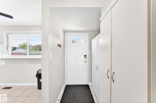 White paneled entry door with an arched glass insert, flanked by light-toned built-in cabinetry with silver-tone hardware - 44 Habitat Crescent Nw, Edmonton, AB 