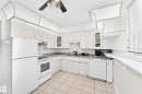 Kitchen featuring white cabinetry, tile flooring, and integrated white appliances - 44 Habitat Crescent Nw, Edmonton, AB 