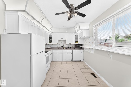 Kitchen featuring white cabinetry, tile flooring, white appliances, and a ceiling fan with integrated lighting - 44 Habitat Crescent Nw, Edmonton, AB 